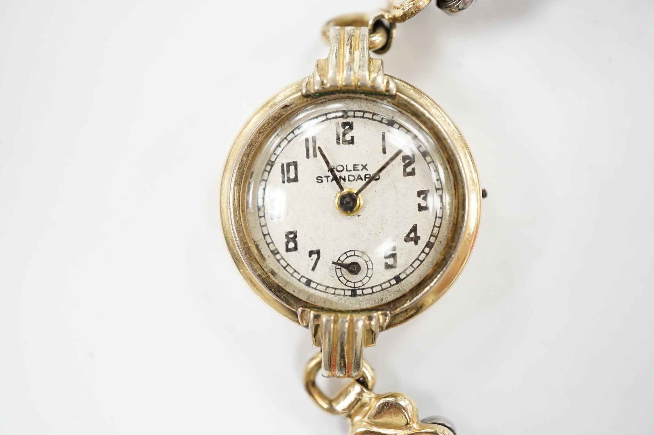 A lady's gilt metal manual wind wrist watch, the dial inscribed 'Rolex Standard', movement unsigned and no winding crown, on an associated flexible link bracelet. Condition - poor